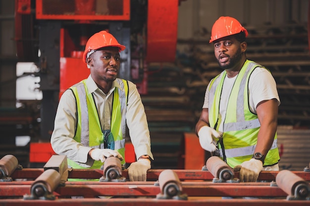 2人の黒人男性アフリカ系アメリカ人労働者が工場で重い機械を制御します