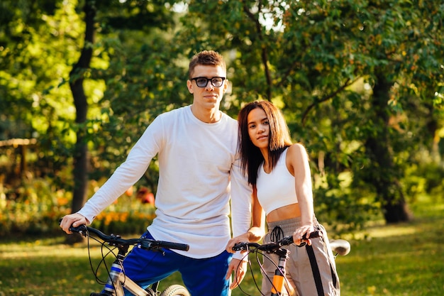 Two people boyfriend and girlfriend are having fun in the park riding bicycles posing for the photo