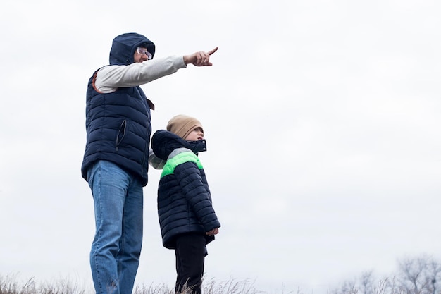 Two people, dad and son on a hill on the background of smoky atmosphere, foggy landscape