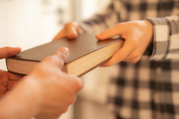 Two people exchange the book, giving the knowledge to younger generations