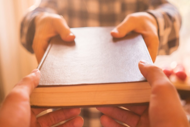 Photo two people exchange the book, giving the knowledge to younger generations