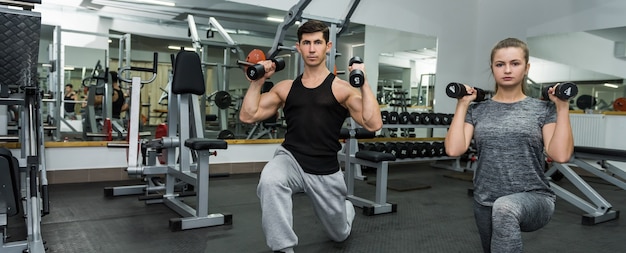 Two people in gym making exercise together