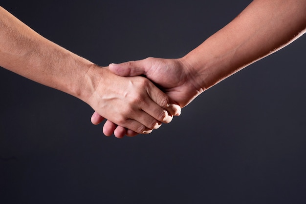 Two people handshaking on a black background