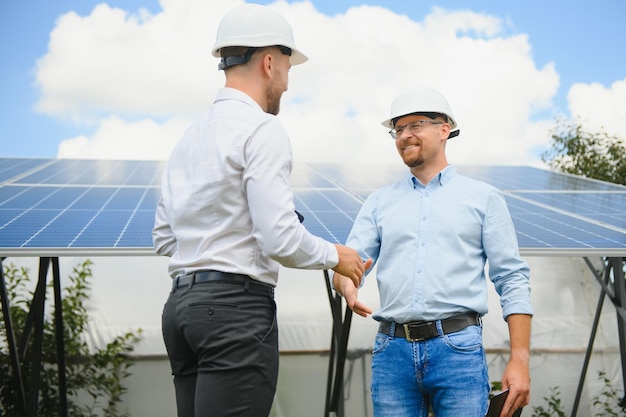 Two people having a shaking hands against solar panel after the conclusion of the agreement in the renewable energy