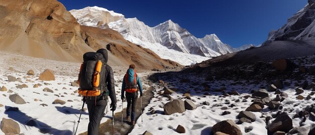 two people hiking in front of a mountain with snow on the ground and mountains in the background