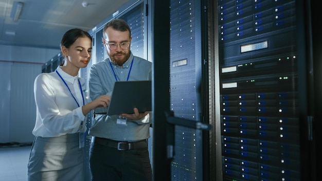 Two people looking at a laptop in a server room