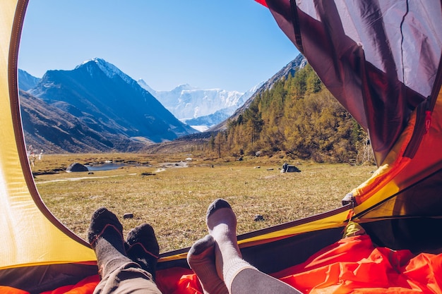 写真 山の景色を眺めながらテントに横たわる 2 人 ベルーハ アッケム湖の谷のテントからの山の眺め アルタイの絵のように美しい谷の眺め