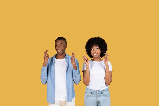 Two people making wishful gestures on yellow