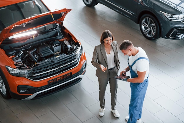 Two people Man repairing woman's automobile indoors Professional service