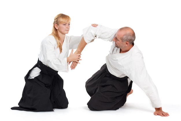 Foto due persone un uomo e una donna praticano l'aikido sul tappeto isolato su sfondo bianco