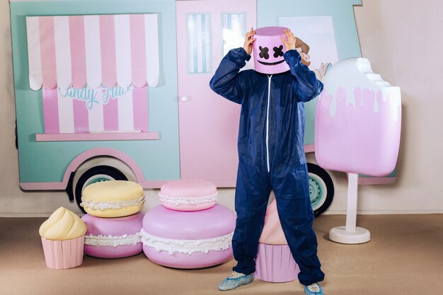 Two people in a marshmallow man suit stand against a white structural background