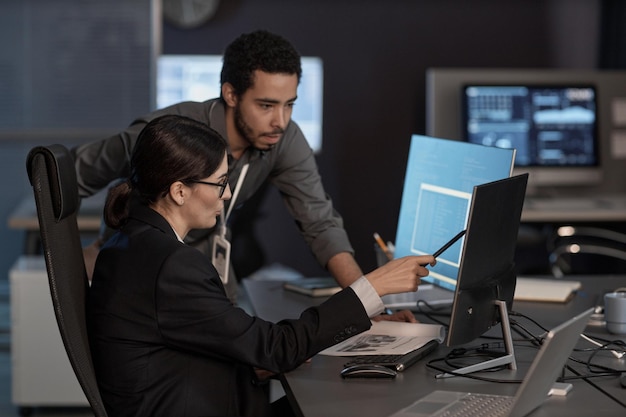 Two people pointing at computer screen while working in IT company