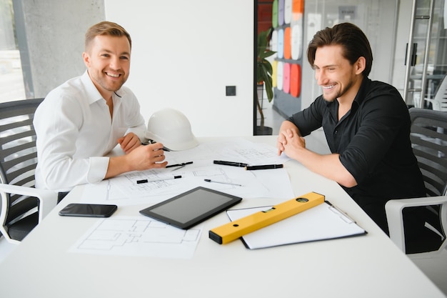 Two people sit in front of construction plan and talk about the architecture