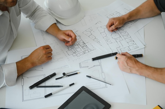 Two people sit in front of construction plan and talk about the\
architecture