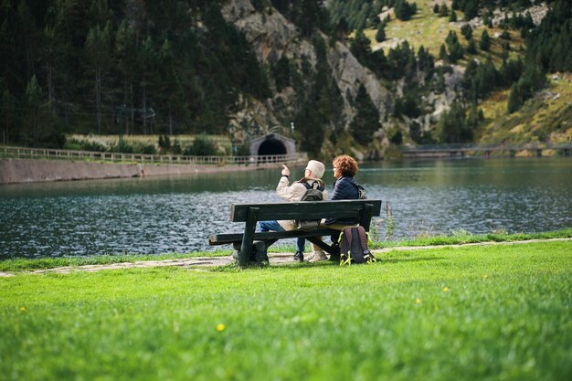 Two people sitting on a bench in front of a lake