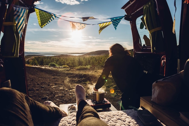 Photo two people sitting in campervan cooking and looking at view