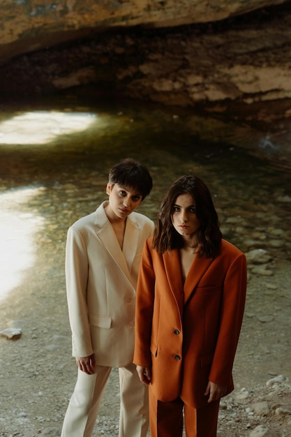 two people in suits stand in front of a body of water