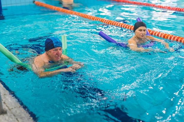 Two people in a swimming pool with one wearing a blue cap and the other wearing a blue cap.