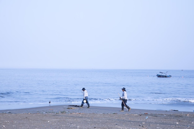 Two people walking on a beach with a boat in the background