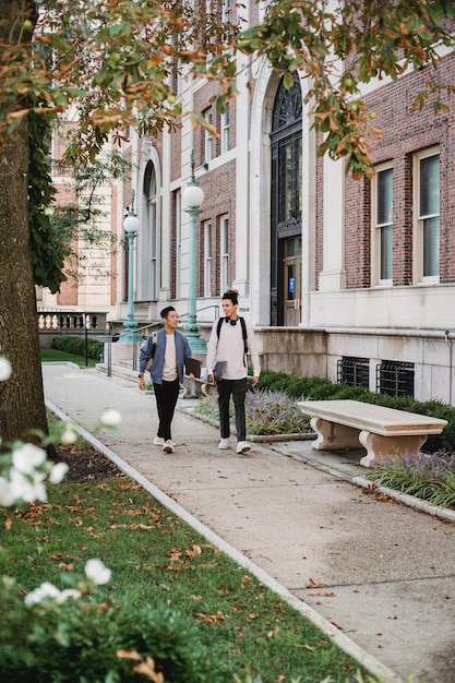 two people walking down a sidewalk in front of a building