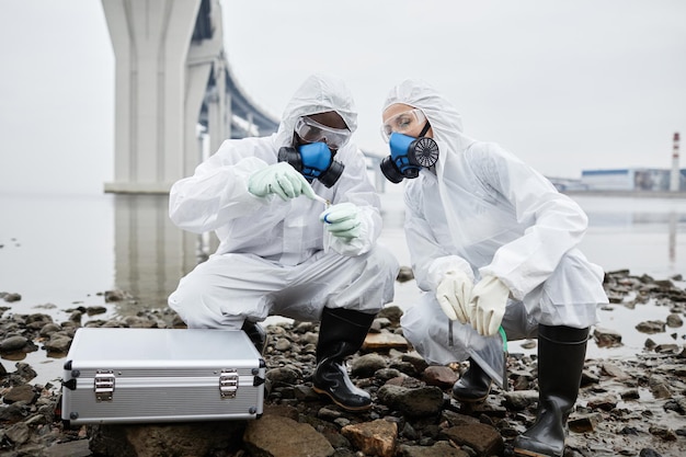 사진 방호복을 입은 두 사람이 물 독성 폐기물과 오염 개념 복사 공간으로 프로브를 수집합니다.