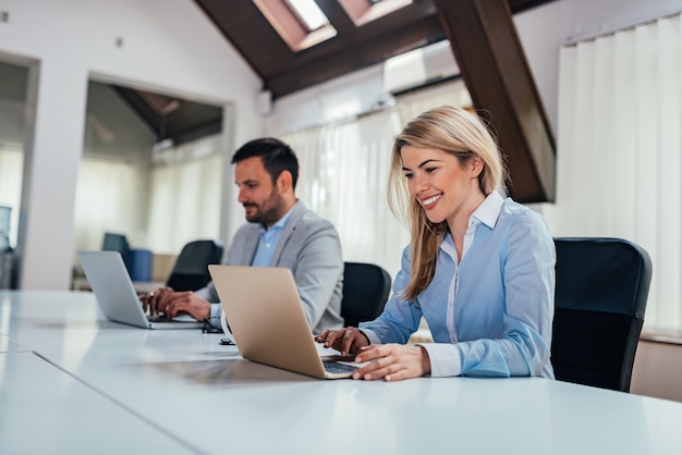 Two people working at laptop computers in coworking office.