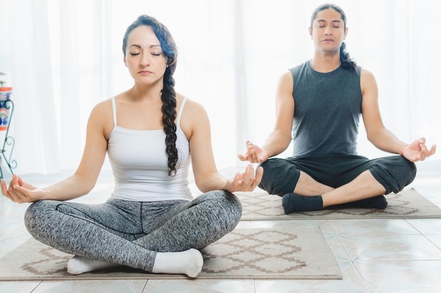 Two people do Yoga indoors there is plenty of light