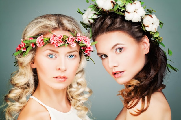 Modello di moda di due donne perfette con capelli ricci lunghi e ghirlanda di fiori estivi. concetto di bellezza, cosmetologia e medicina estetica