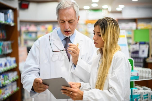 Two pharmacists talking while working on tablet in their store