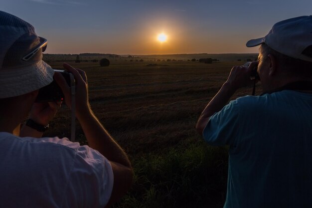 Two photographers shooting dawn on field