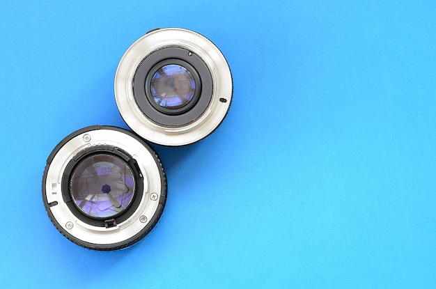 Two photographic lenses lie on a bright blue background. Space for text