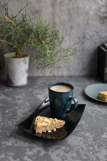 Foto due pezzi di torta di mandorle e tazza di caffè sul vassoio nero