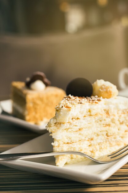 Photo two pieces of cake on a table in a cafe with dessert fork.