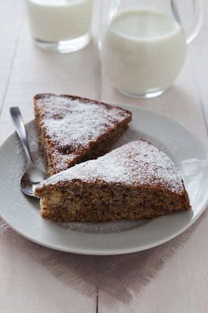 Two pieces of cake with sugar powder and milk