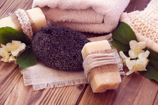 Two pieces of dry soap with a jasmine, towel, pumice and a bast