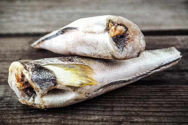 Two pieces of frozen hake fish on wooden background