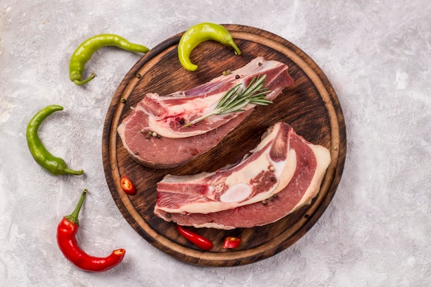 Two pieces of raw beef brisket on the bone with hot chili on a light background.