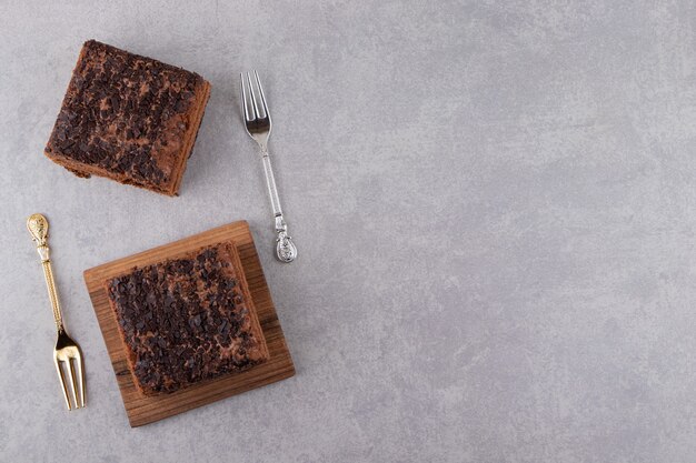 Two pieces of sweet chocolate cake on stone table.