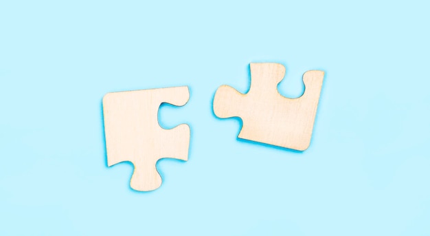 Due pezzi di un puzzle in legno su sfondo blu il concetto di trovare le giuste soluzioni nel lavoro di squadra copiare lo spazio