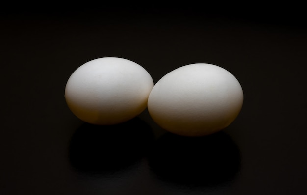 Two pigeon eggs close up top view on a dark background