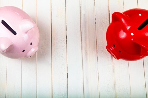 Two pigs piggy banks on a white wooden background, top view. Accumulation of money.