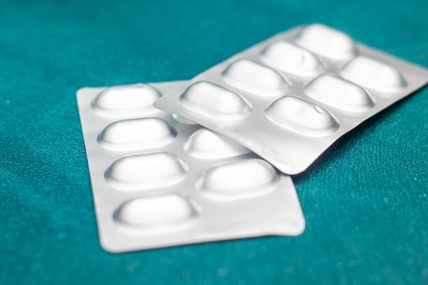 Photo two pill blister packs on green surface in medical setting