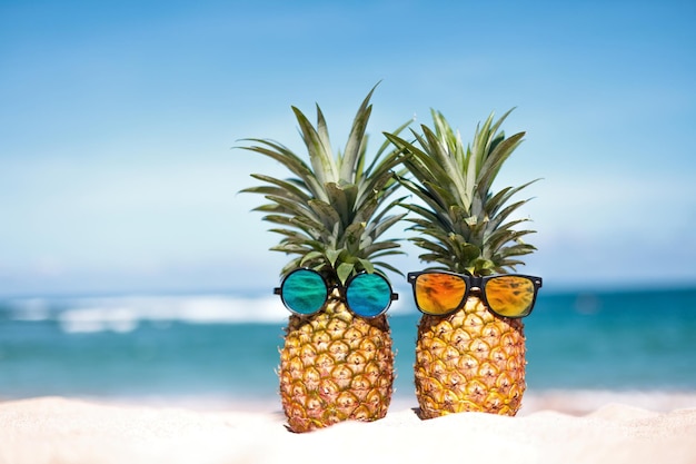 Photo two pineapples with trendy sunglasses in tropical paradise