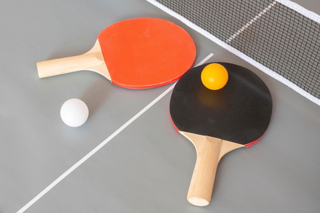 two ping pong table tennis rackets and balls on a gray table