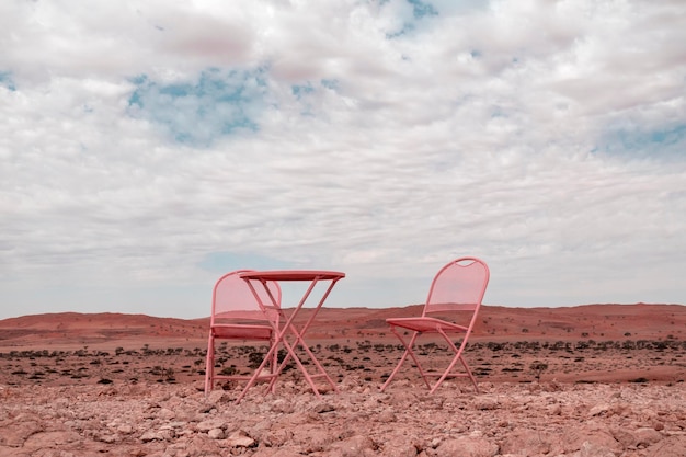 사진 두 개의 분홍색 의자 와 한 개의 테이블 이 구름진 하늘 을 배경 으로 나미브 사막 에 서 있다