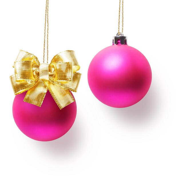 Two pink christmas balls decorated with gold bow hanging on ribbon