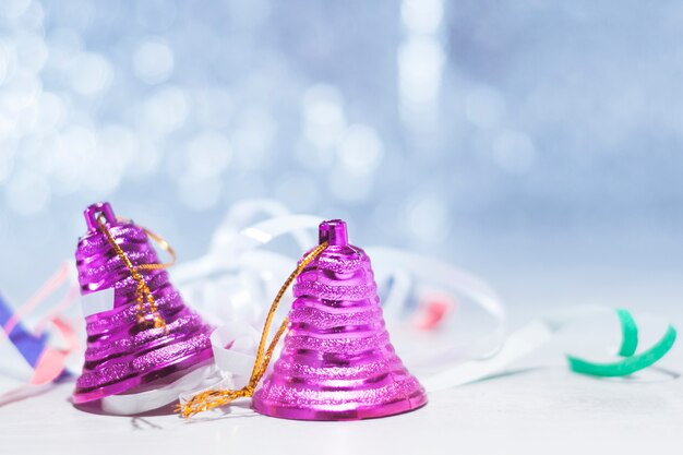 Two pink Christmas bells on a table with festive tinsel on a blue