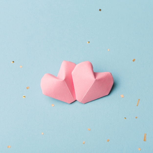 Two pink hearts and Golden tinsel on a light blue background