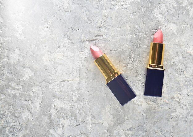 Two pink lipsticks on a gray concrete.
