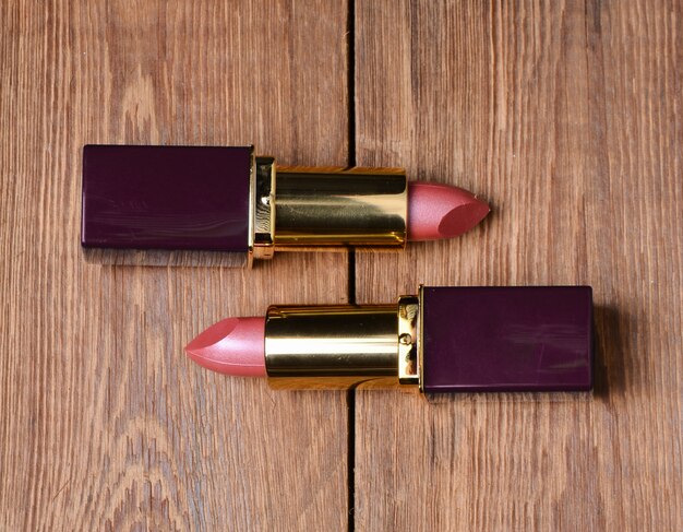 Two pink lipsticks on a wooden table.